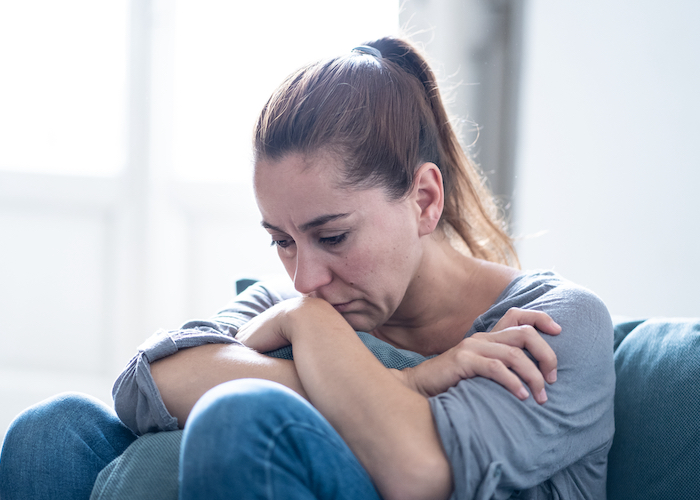 A woman sitting on a couch looking despondent